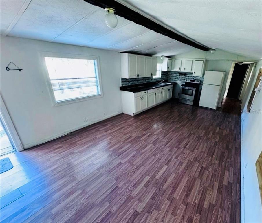 A kitchen with white cabinets, dark countertops, and wood-look flooring in an open room — 13330 SW 9TH LANE, OCALA, FL