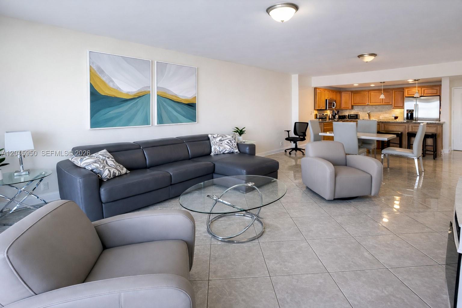 An open-concept living and dining area features tile flooring, a grey sectional, and wood cabinetry — 2101 S Ocean Dr # 606, Hollywood FL 33019, HOLLYWOOD, FL