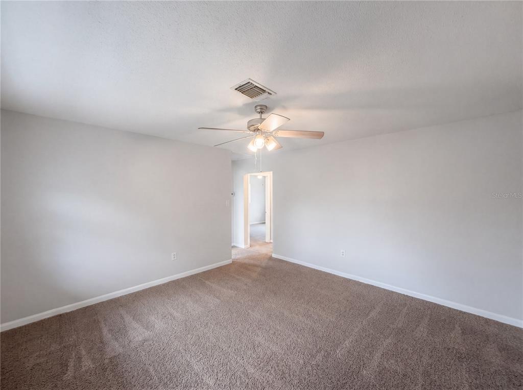An empty bedroom features light gray walls, beige carpeting, and a ceiling fan — 1100 CAREFREE COVE DRIVE, WINTER HAVEN, FL