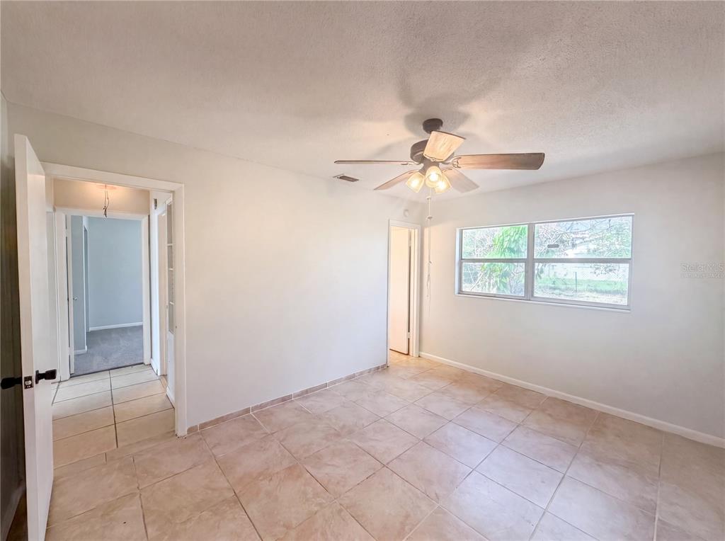 A bedroom with light-colored tile flooring, a ceiling fan, and two doorways — 1100 CAREFREE COVE DRIVE, WINTER HAVEN, FL