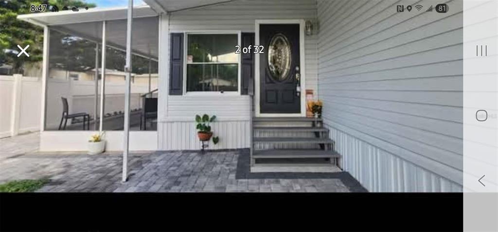 A mobile home exterior features a screened porch, a dark front door, and paved patio — 6985 MEDITERRANEAN ROAD, ORLANDO, FL