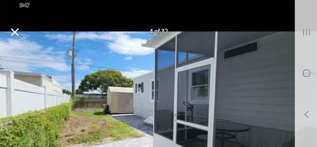 A screened-in porch sits beside a mobile home with a small shed in the yard — 6985 MEDITERRANEAN ROAD, ORLANDO, FL
