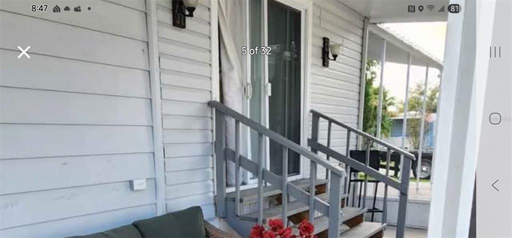A white-sided exterior wall features a sliding glass door and wooden stairs leading outside — 6985 MEDITERRANEAN ROAD, ORLANDO, FL