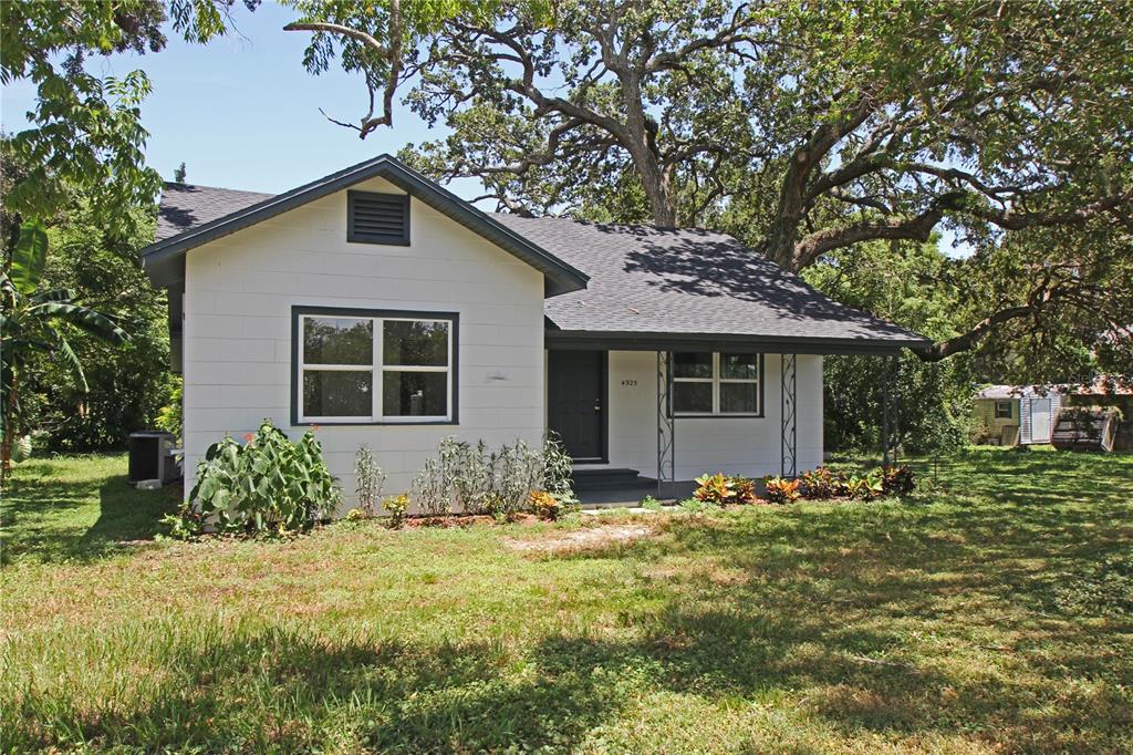 A single-story white house with a dark roof and a front porch sits on grass — 4925 MAGNOLIA AVENUE, MULBERRY, FL