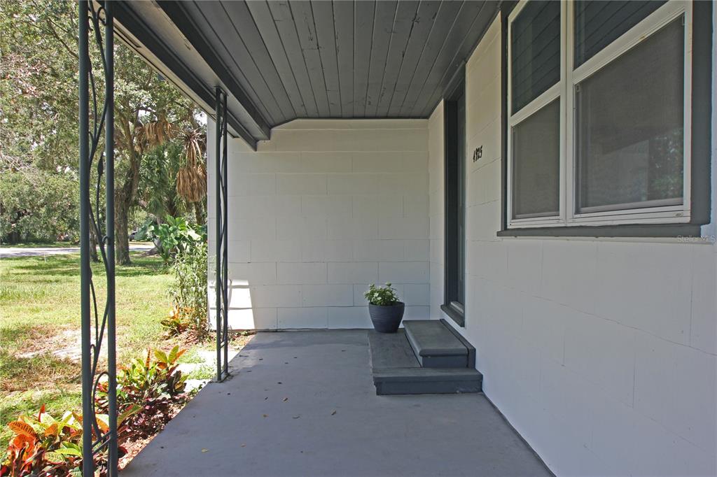 A covered porch features a concrete floor, white block walls, and steps leading to a doorway — 4925 MAGNOLIA AVENUE, MULBERRY, FL