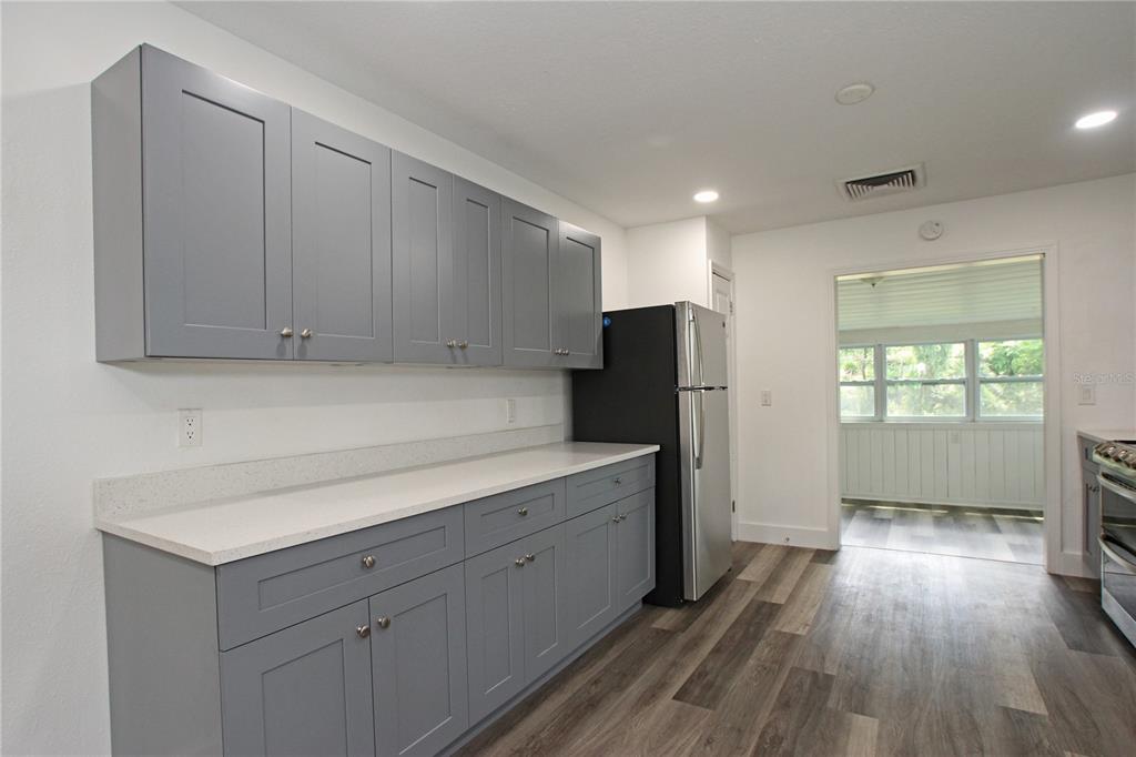 A kitchen features gray shaker cabinets, white countertops, a black refrigerator, and wood-look flooring — 4925 MAGNOLIA AVENUE, MULBERRY, FL