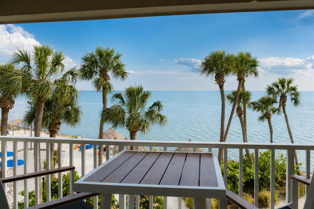 A balcony with a table overlooks palm trees, a sandy beach, and the ocean — 2506 N ROCKY POINT DRIVE UNIT 331, TAMPA, FL