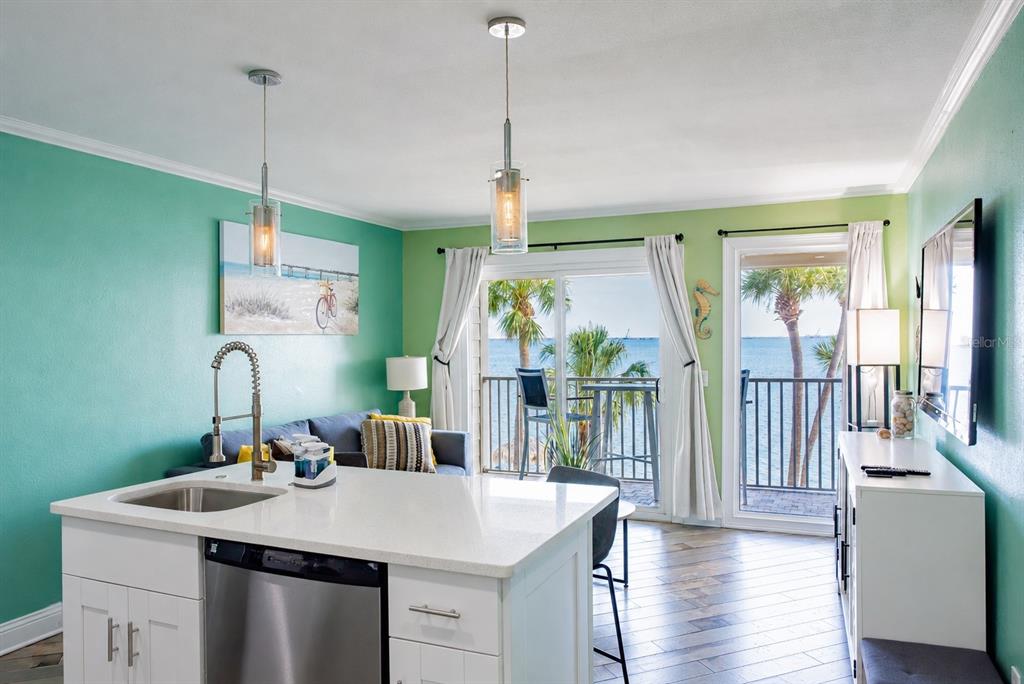 A kitchen island with a sink overlooks a living area with a water view balcony — 2506 N ROCKY POINT DRIVE UNIT 331, TAMPA, FL