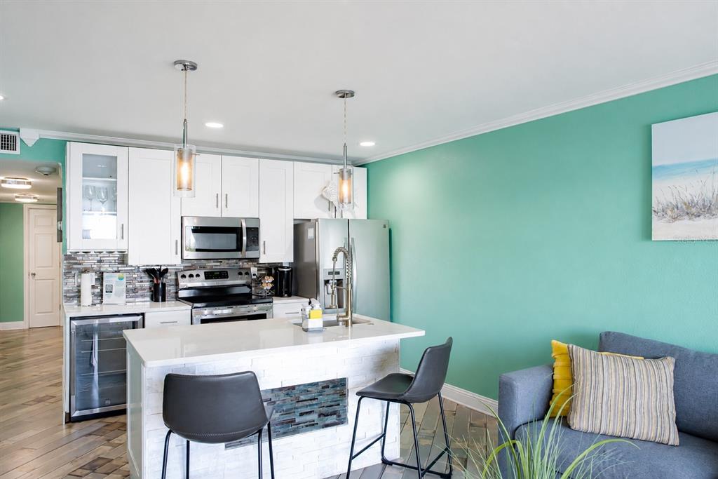 A kitchen features white cabinets, stainless steel appliances, a stone-tiled island, and a teal wall — 2506 N ROCKY POINT DRIVE UNIT 331, TAMPA, FL