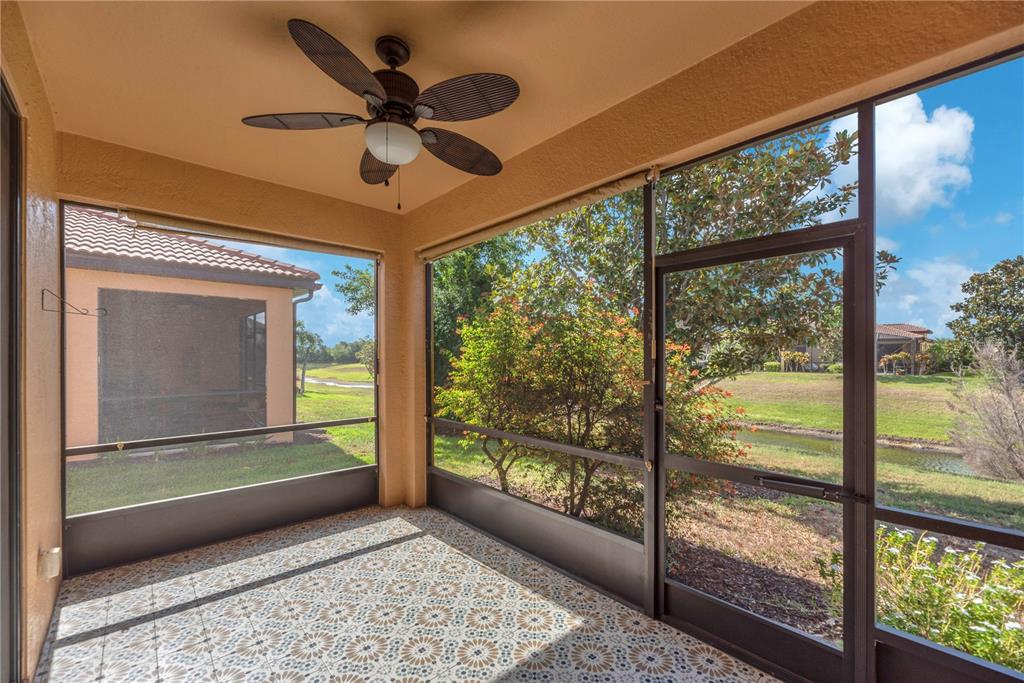 A screened-in porch features patterned tile flooring, a ceiling fan, and views of a pond — 107 SHELL FALLS DRIVE, APOLLO BEACH, FL