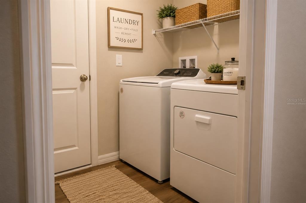 A laundry room features a washer, dryer, wall sign, and a wire shelf with baskets — 1341 DERRY AVENUE, HAINES CITY, FL
