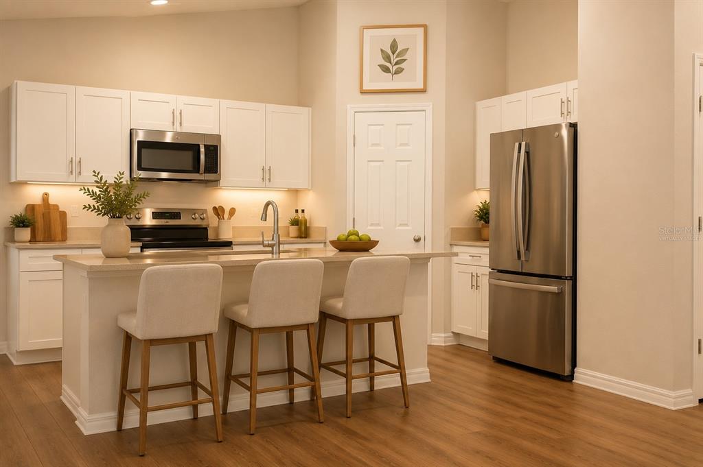 A modern kitchen features white cabinets, stainless steel appliances, a center island, and wood flooring — 1341 DERRY AVENUE, HAINES CITY, FL