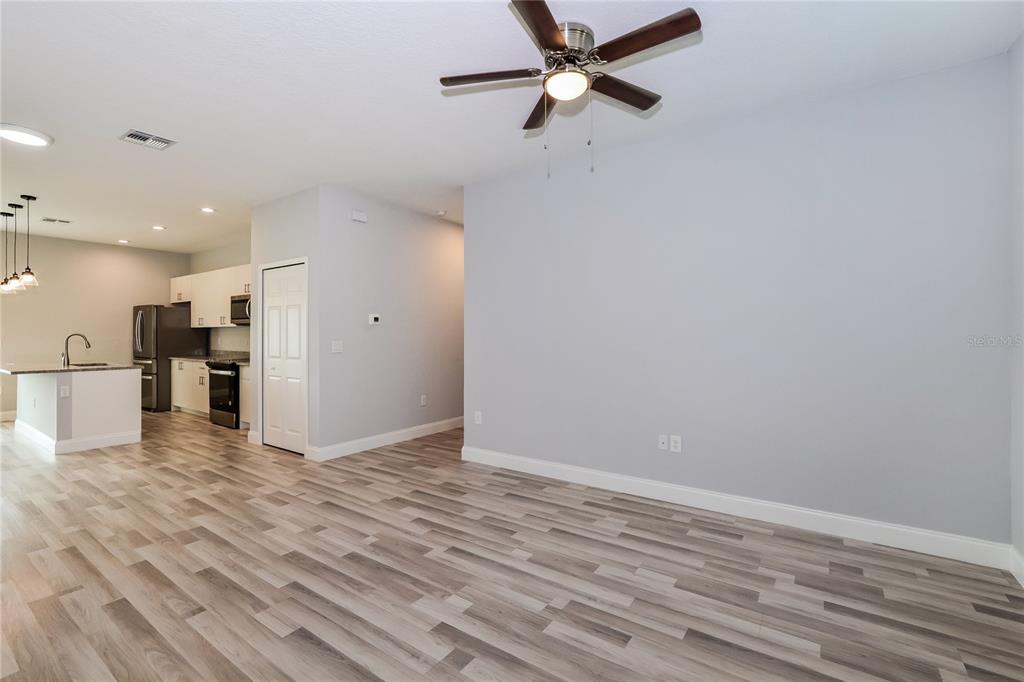A living area with light gray walls, wood-look flooring, and a ceiling fan — 102 CONCH WAY, POINCIANA, FL