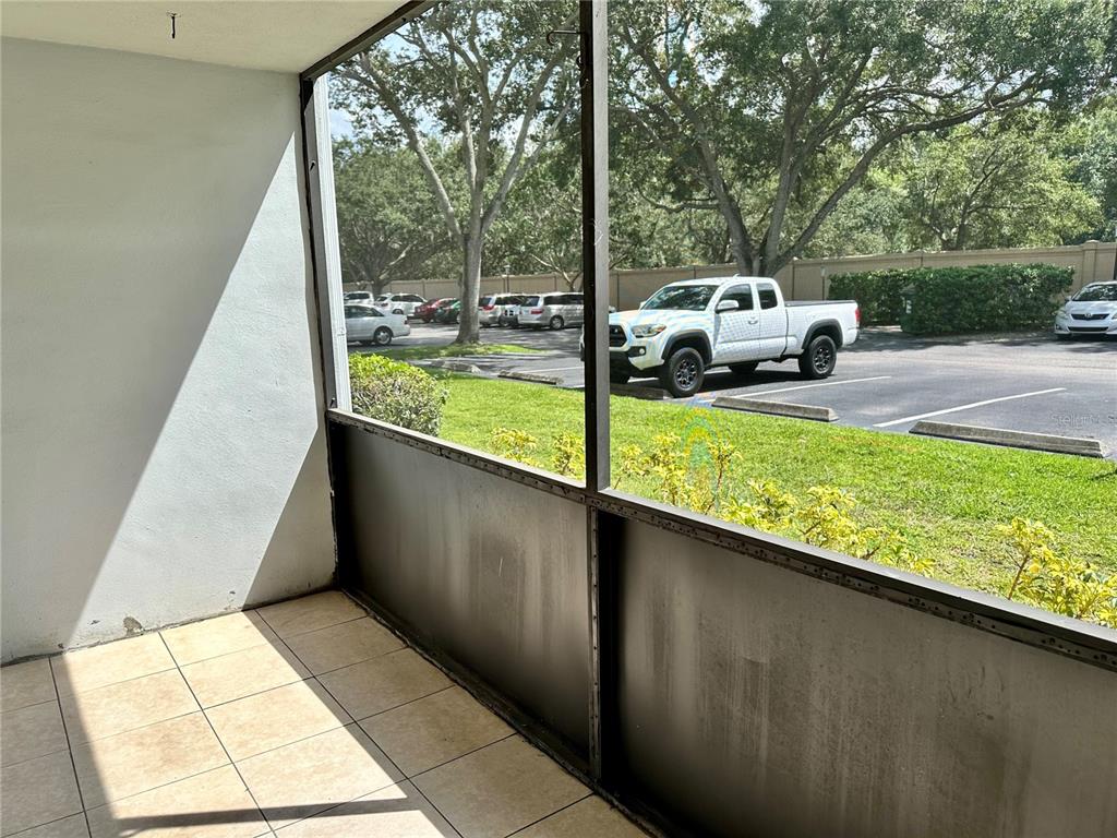 A screened-in patio with tiled flooring overlooks a parking lot with several parked vehicles — 8205 SUN SPRING CIRCLE UNIT B1, ORLANDO, FL
