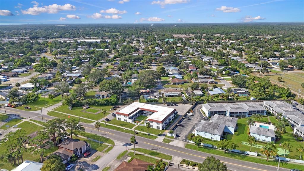 An aerial view shows apartment complexes, residential houses, and streets surrounded by trees and greenery — 955 KNOX MCRAE DRIVE, TITUSVILLE, FL