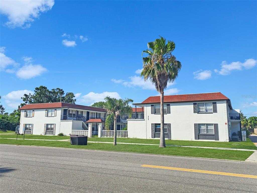 A two-story apartment building with a white exterior, red roof, and palm trees in front — 955 KNOX MCRAE DRIVE, TITUSVILLE, FL
