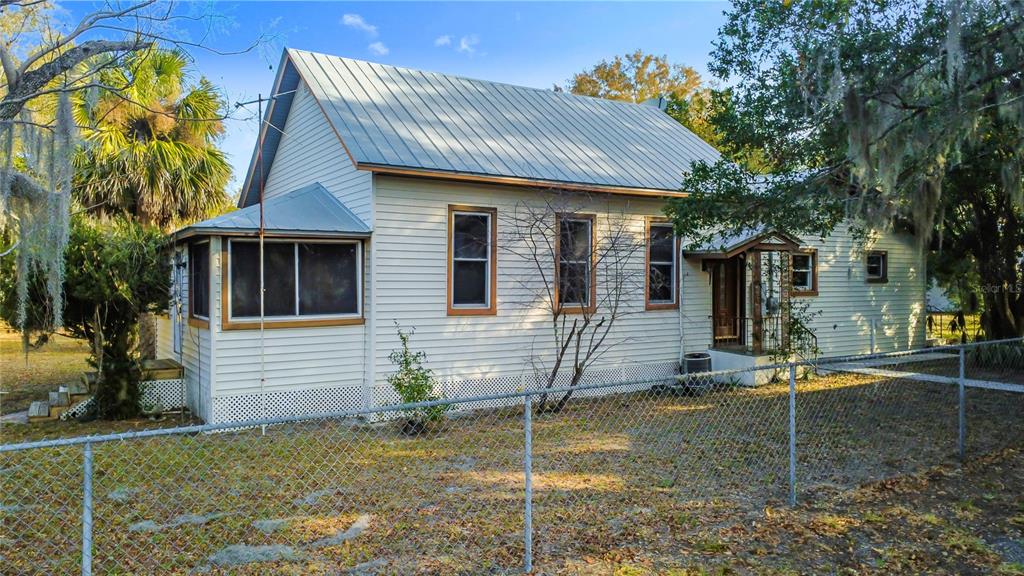 A light-colored house with a metal roof and a chain-link fence in the yard — 5759 LAKE STREET, MOUNT DORA, FL