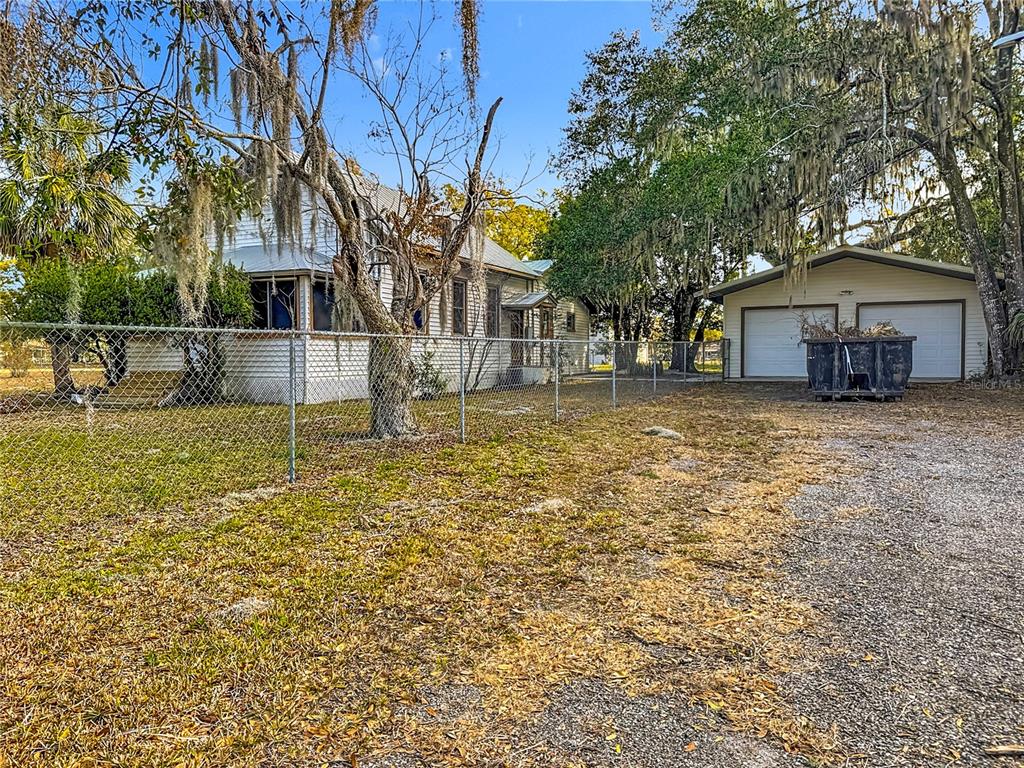 A white house with a detached two-car garage sits behind a chain-link fence — 5759 LAKE STREET, MOUNT DORA, FL