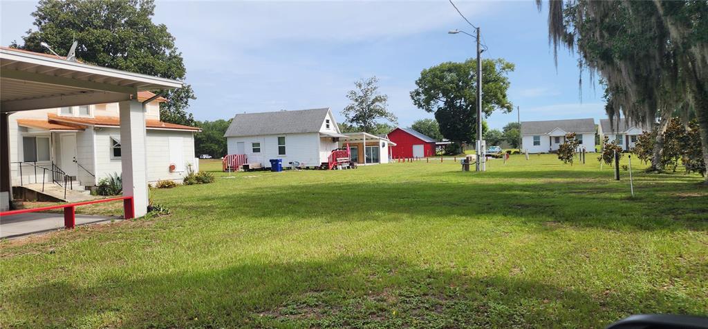 A grassy yard features several small white houses and a red barn under a blue sky — 110 E 2ND AVENUE, PIERSON, FL