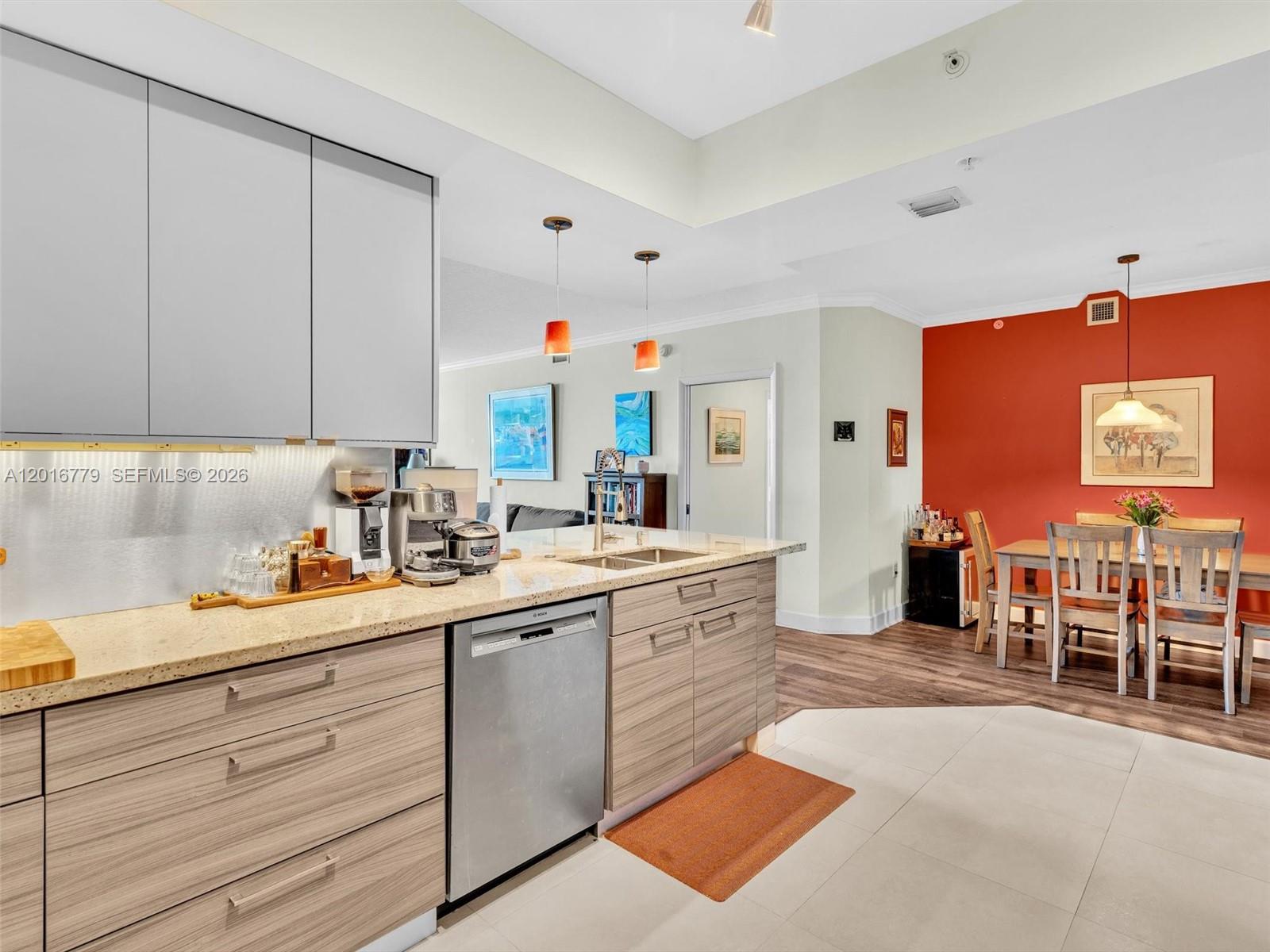 A kitchen with wood-grain cabinets and a stainless steel dishwasher opens to a dining area — 2000 N Bayshore Dr # 220, Miami FL 33137, MIAMI, FL