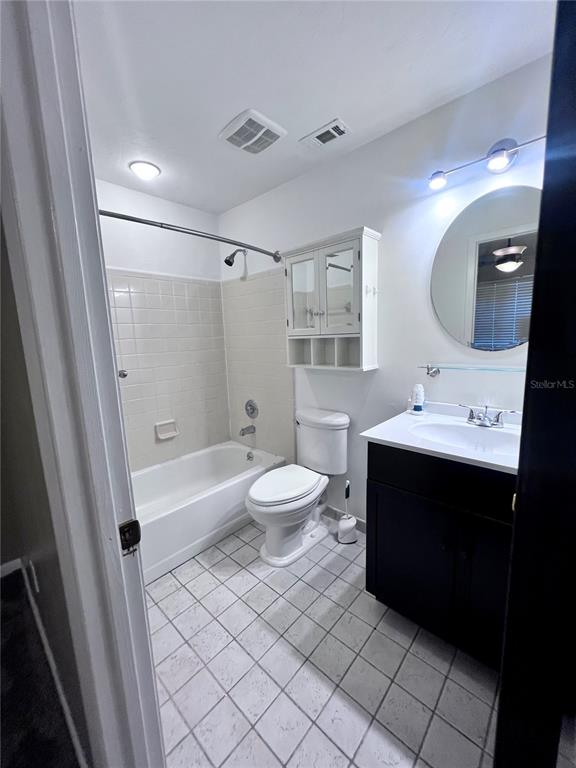 A bathroom featuring a tub-shower combination, a white toilet, and a dark wood vanity — 2735 SW 35TH PLACE UNIT 2004, GAINESVILLE, FL