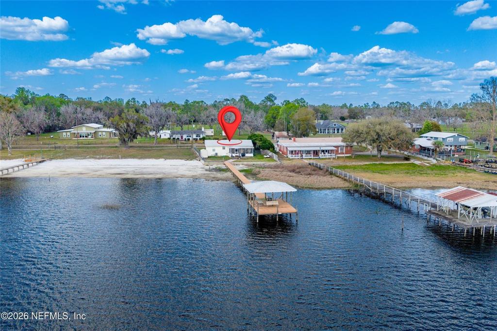 An aerial view shows a waterfront house with a long wooden dock and pier — 7932 SW COUNTY ROAD 18, HAMPTON, FL
