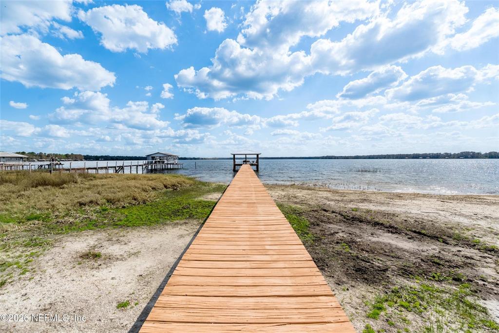 A wooden dock extends into a large lake under a blue sky with clouds — 7932 SW COUNTY ROAD 18, HAMPTON, FL