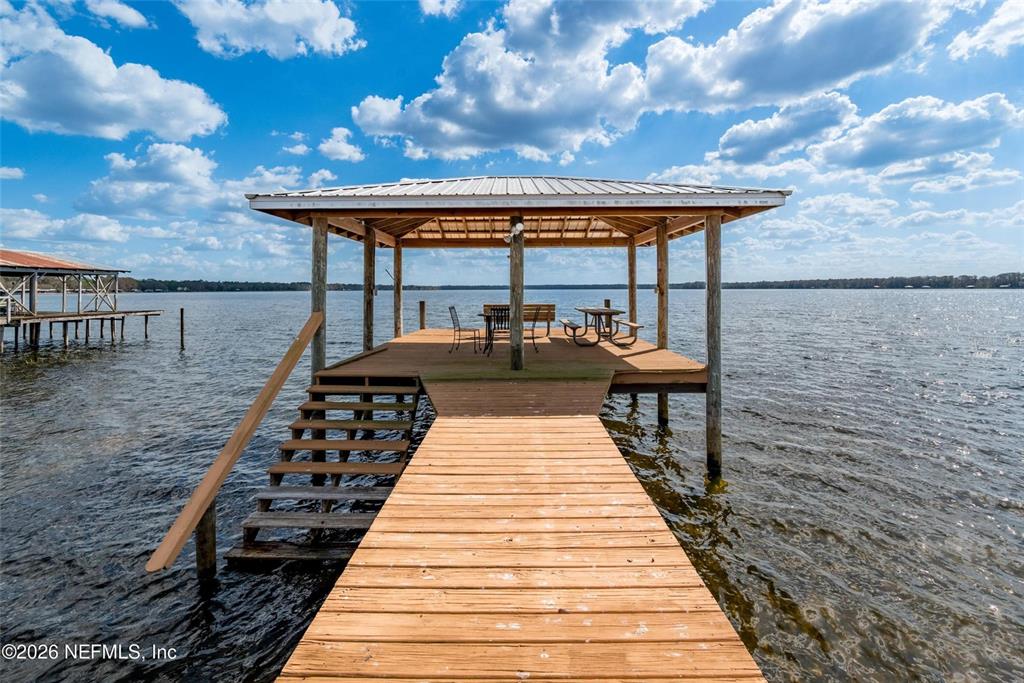 A wooden dock with a covered pavilion extends over a lake under a cloudy sky — 7932 SW COUNTY ROAD 18, HAMPTON, FL