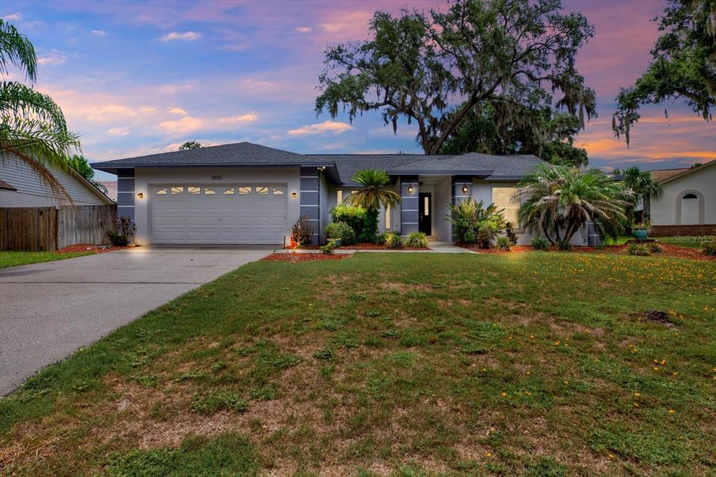 A single-story house with a two-car garage, gray exterior, and a large front yard — 1805 TAWNEE PLACE, BRANDON, FL