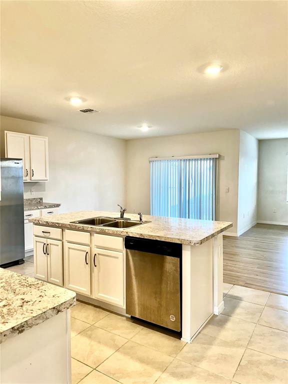 A kitchen features white cabinets, a granite-topped island with a dishwasher, and tile flooring — 939 SUN BURST ROAD, WINTER HAVEN, FL