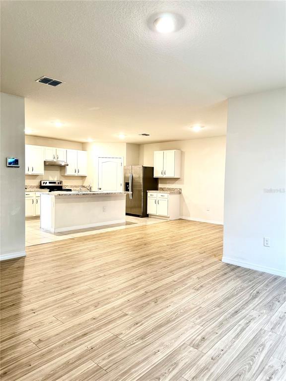 A kitchen with white cabinets, a center island, and light-colored wood-look flooring — 939 SUN BURST ROAD, WINTER HAVEN, FL