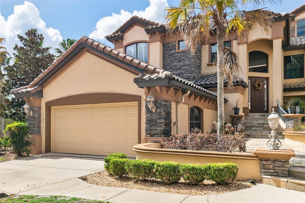 A two-story house with a beige stucco exterior, stone accents, and a two-car garage — 1105 W POINTE VISTA PATH UNIT 43, HERNANDO, FL