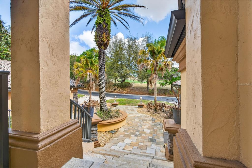 A view from a stone staircase looking out toward a palm tree and driveway — 1105 W POINTE VISTA PATH UNIT 43, HERNANDO, FL
