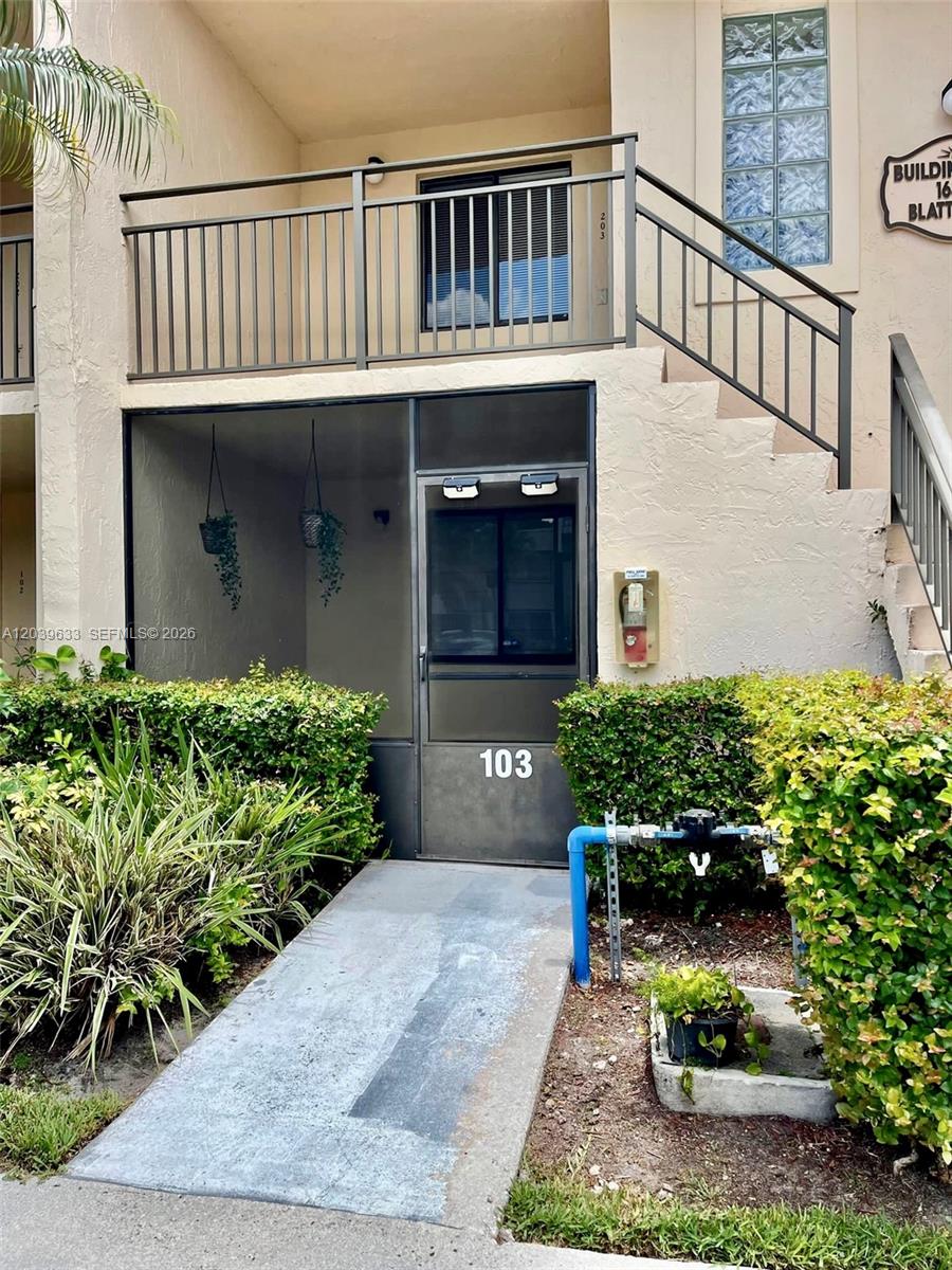 The exterior of a ground-floor apartment unit features a screened entrance, stairs, and landscaping — 16461 Blatt Blvd # 103, Weston FL 33326, WESTON, FL