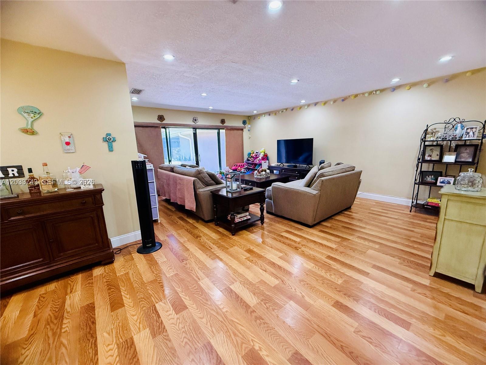 A living room features hardwood floors, beige walls, recessed lighting, and two gray sofas — 103 Tweedbrook Ln # 101, Hollywood FL 33021, HOLLYWOOD, FL
