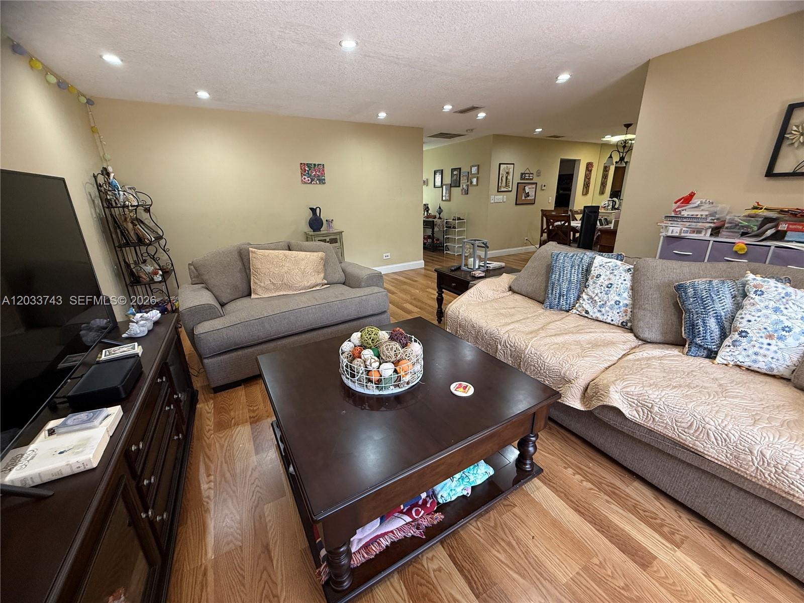 A living room features a dark wood coffee table, two gray sofas, and hardwood flooring — 103 Tweedbrook Ln # 101, Hollywood FL 33021, HOLLYWOOD, FL