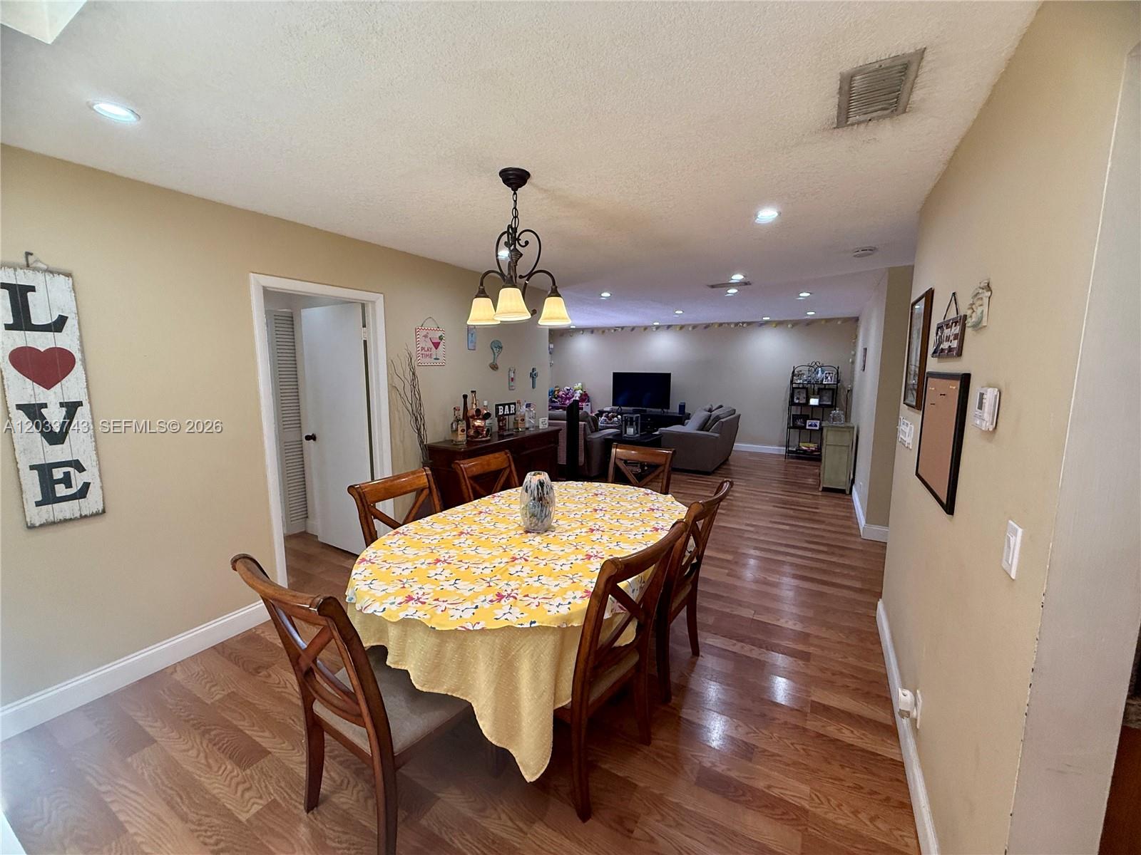 A dining area with a floral tablecloth and wooden chairs opens into a living room — 103 Tweedbrook Ln # 101, Hollywood FL 33021, HOLLYWOOD, FL