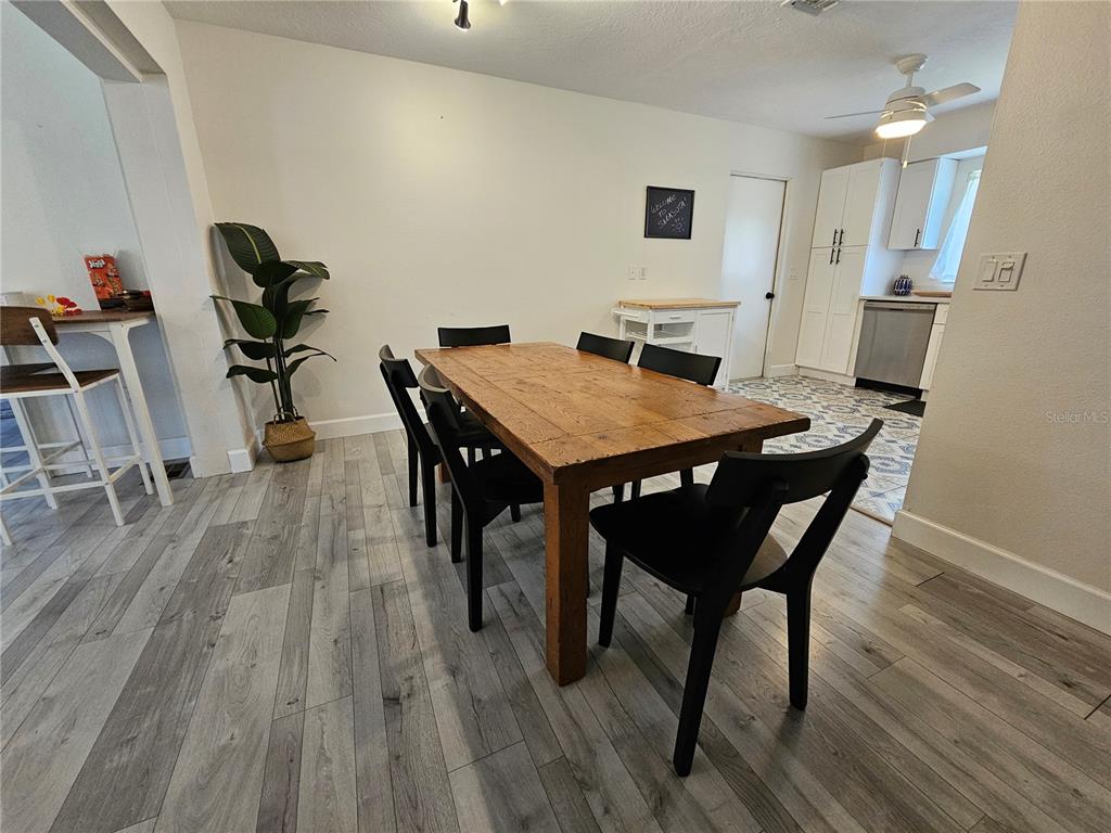 A dining area features a wooden table, black chairs, and light wood-look flooring — 6442 COLONIAL DRIVE, SARASOTA, FL