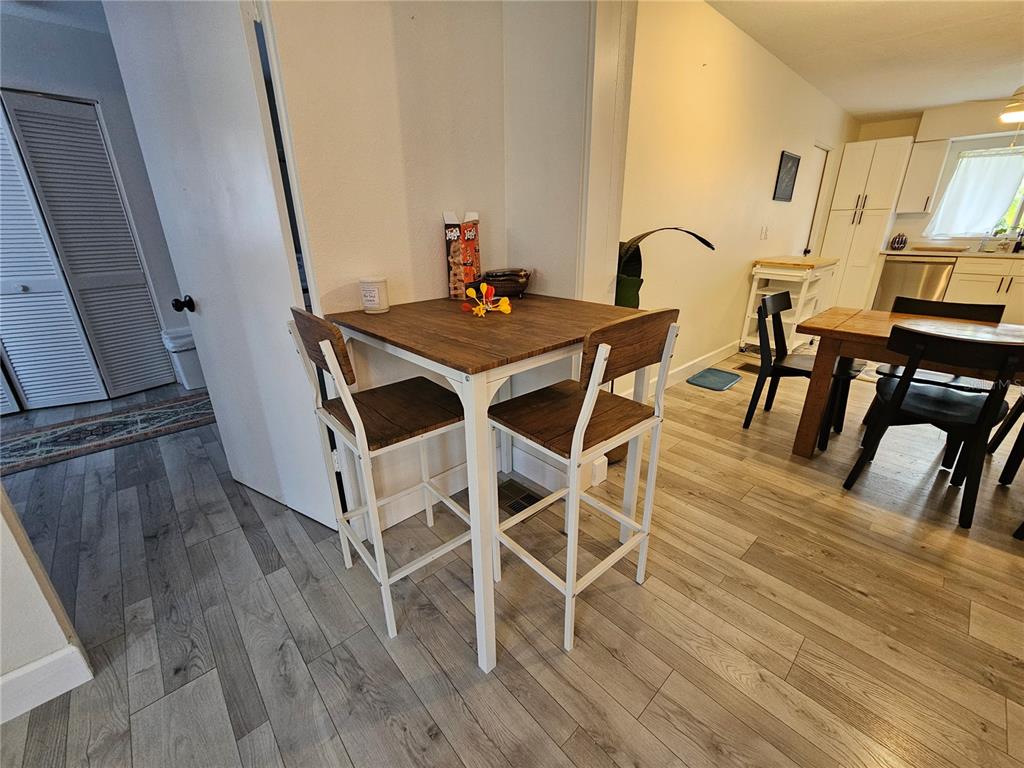 A small dining area features a square wooden table with two stools and light flooring — 6442 COLONIAL DRIVE, SARASOTA, FL