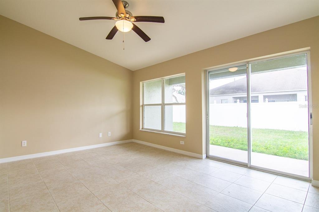 A dining area with gray walls, tile flooring, a ceiling fan, and sliding glass doors — 402 BRIDGEWATER COURT, KISSIMMEE, FL