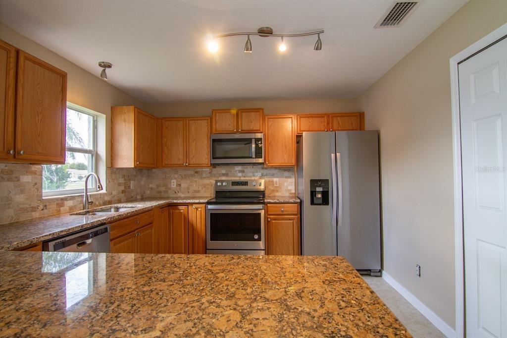 An empty room with light gray walls, tile flooring, a ceiling fan, and sliding glass doors — 402 BRIDGEWATER COURT, KISSIMMEE, FL