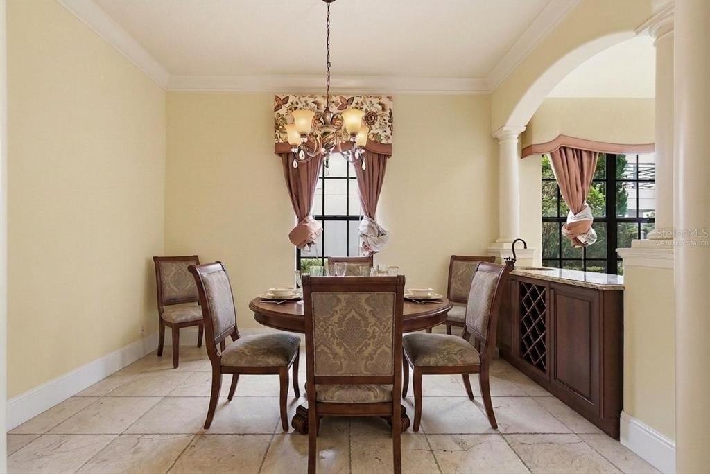 A dining room features a round wooden table, upholstered chairs, tile flooring, and a wine rack — 877 DESERT MOUNTAIN COURT, KISSIMMEE, FL