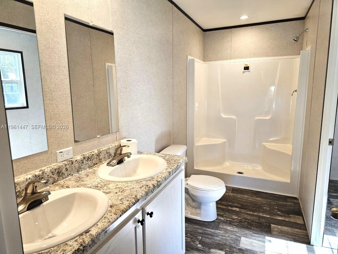 A bathroom features a double vanity with granite countertops, a toilet, and a shower stall — 881 WOODLAND BLVD # 0, Clewiston FL 33440, CLEWISTON, FL