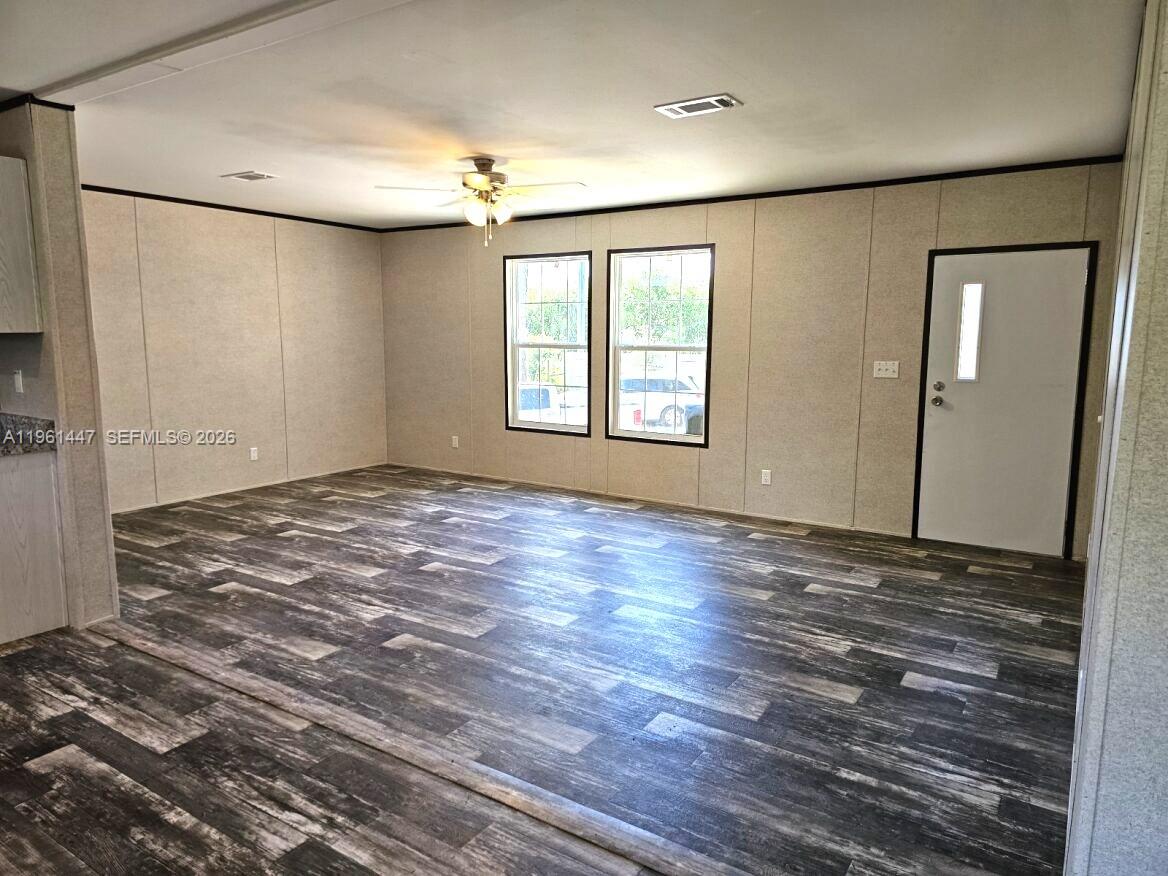 An empty living room features light-colored paneled walls, dark wood-look flooring, and a ceiling fan — 881 WOODLAND BLVD # 0, Clewiston FL 33440, CLEWISTON, FL