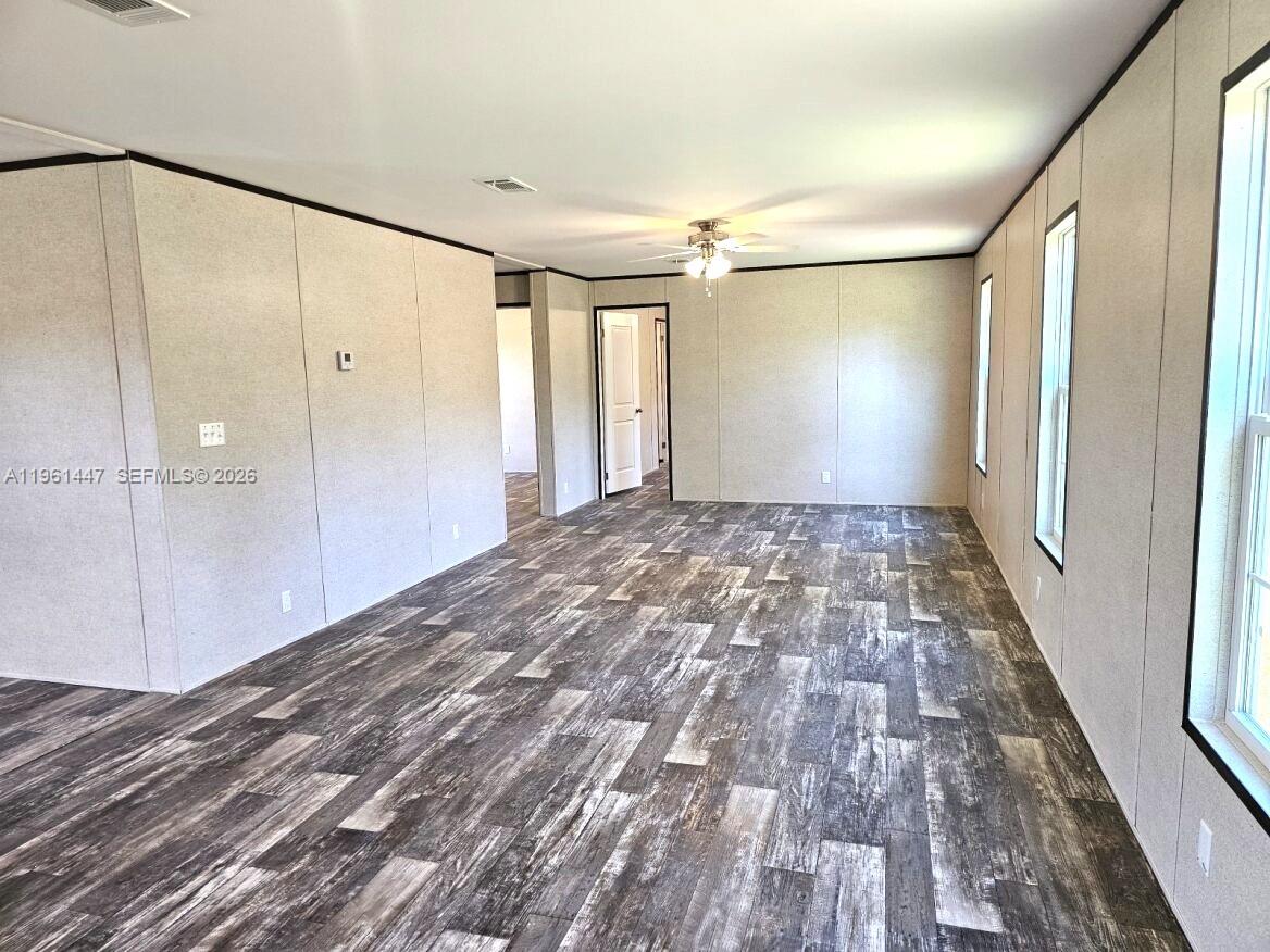 An empty room features light-colored paneled walls, wood-look flooring, and a ceiling fan — 881 WOODLAND BLVD # 0, Clewiston FL 33440, CLEWISTON, FL