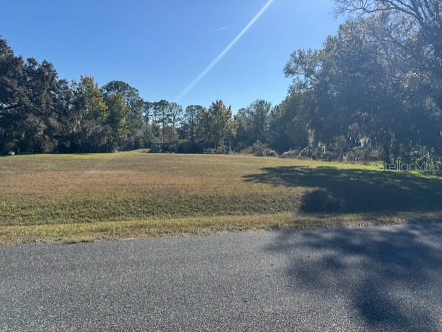 A vacant, grassy lot is bordered by trees under a clear blue sky — Lots SW 229TH COURT, DUNNELLON, FL