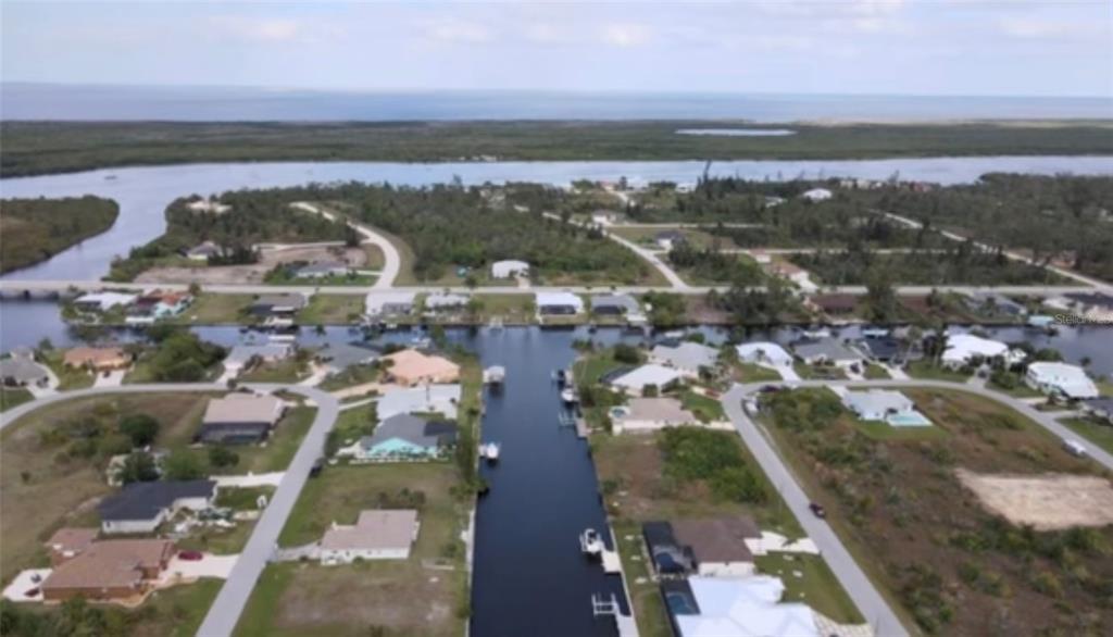 An aerial view shows a residential neighborhood with houses situated along a canal and coastline — 15442 MCCOMB CIRCLE, PORT CHARLOTTE, FL