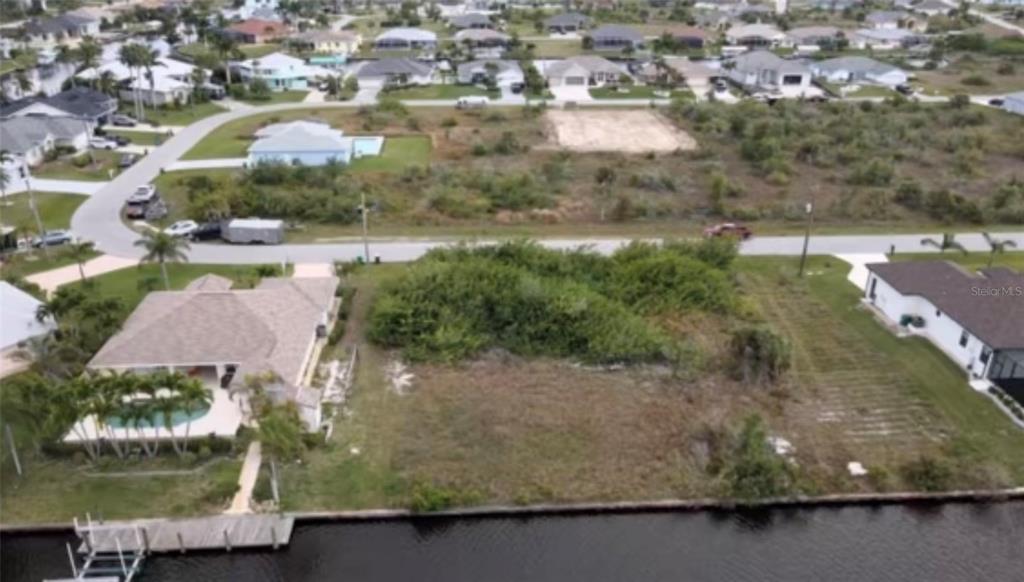 An aerial view shows a vacant waterfront lot situated between two existing residential homes — 15442 MCCOMB CIRCLE, PORT CHARLOTTE, FL