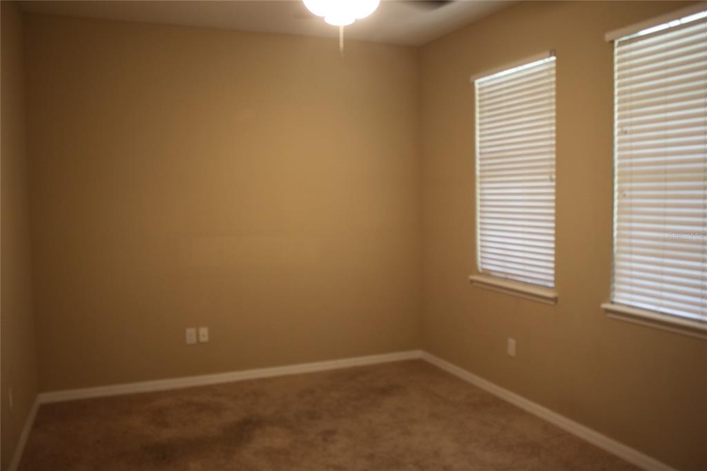 An empty room with beige walls, tan carpet, and two windows with white blinds — 13231 OVERSTREET ROAD, WINDERMERE, FL