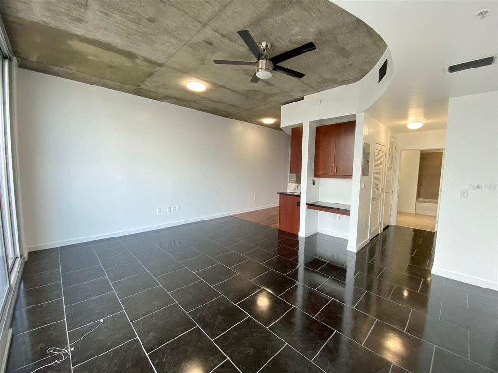 A living room with a concrete ceiling, black tile flooring, and a built-in desk area — 155 S COURT AVENUE UNIT 1603, ORLANDO, FL